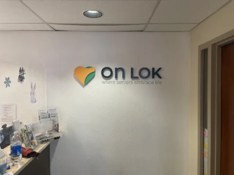 On Lok dimensional wall logo beside restroom identification signs