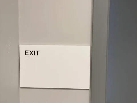 White exit direction sign installed beside an interior door