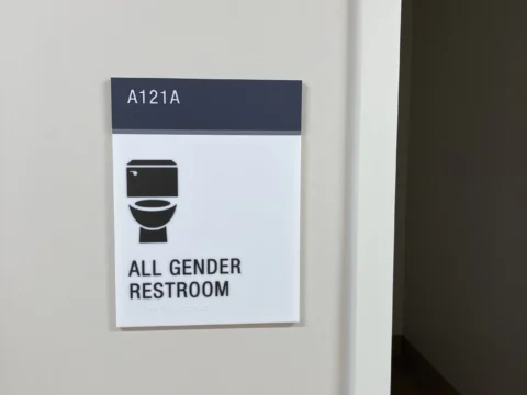 All-gender accessible restroom sign installed beside the entrance