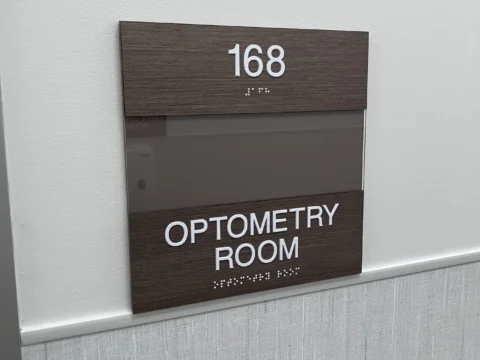 Optometry room 168 identification plaque with wood-look header