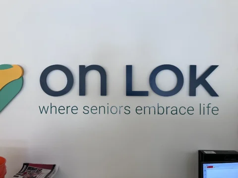 On Lok dimensional logo and tagline mounted on an interior wall