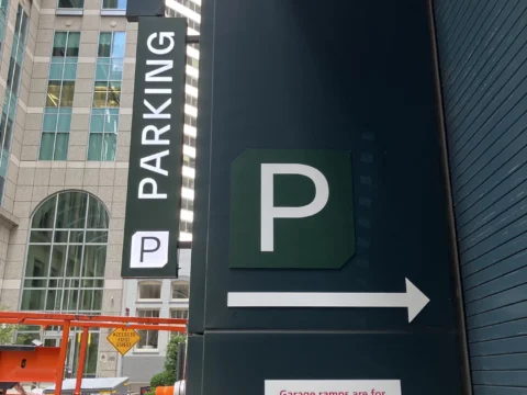 Parking direction sign mounted beside a downtown entrance