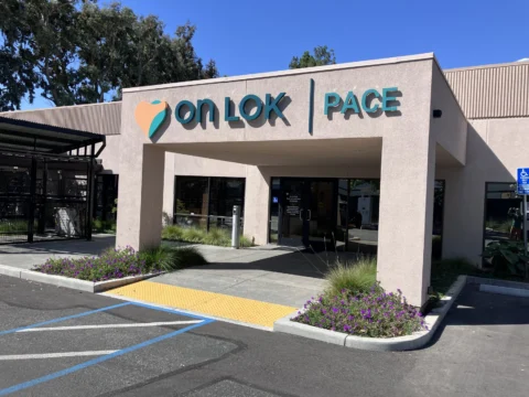 Angled view of On Lok PACE entrance signage and accessible parking