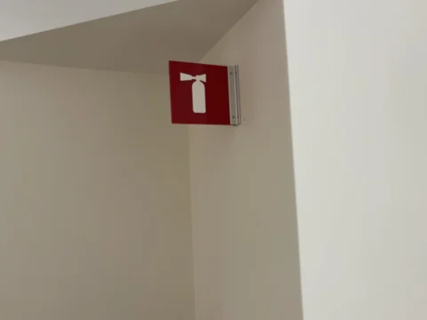 Red fire extinguisher location sign mounted on a corridor wall