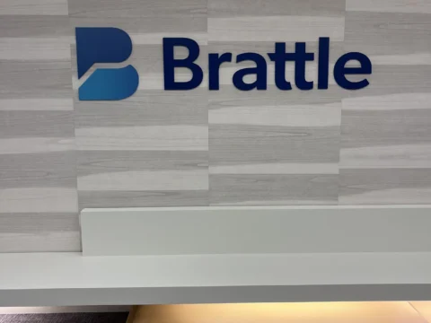 Brattle dimensional logo on a gray patterned feature wall