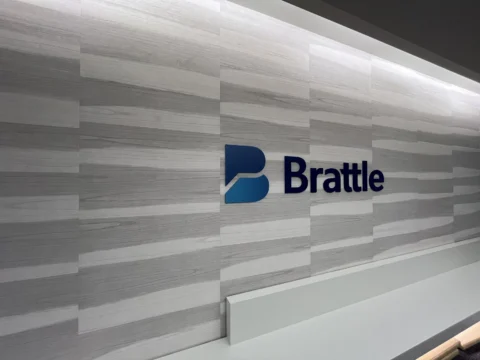 Close view of Brattle branding on a layered gray wall graphic