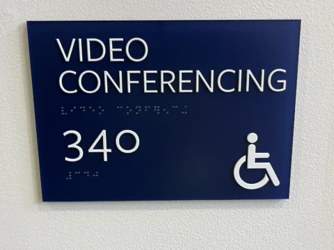 Close view of accessible video conferencing room 340 signage