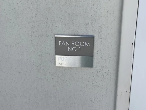 Metal equipment room identification plaque beside a door