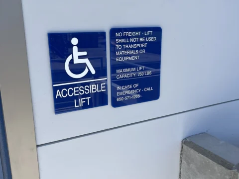 Wheelchair-accessible lift sign installed beside a platform lift
