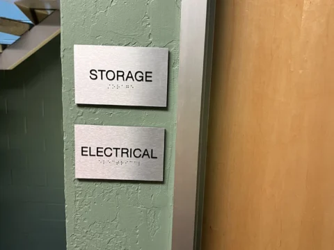 Storage and electrical room identification plaques beside a door