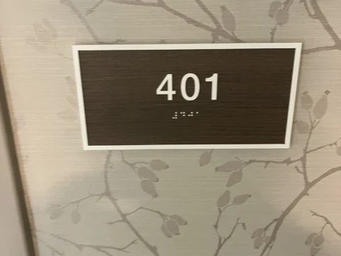 Room 401 identification plaque mounted over a map-patterned wall