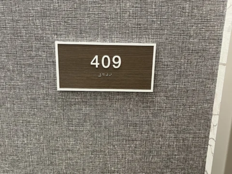 Room 409 identification plaque installed on a textured wall