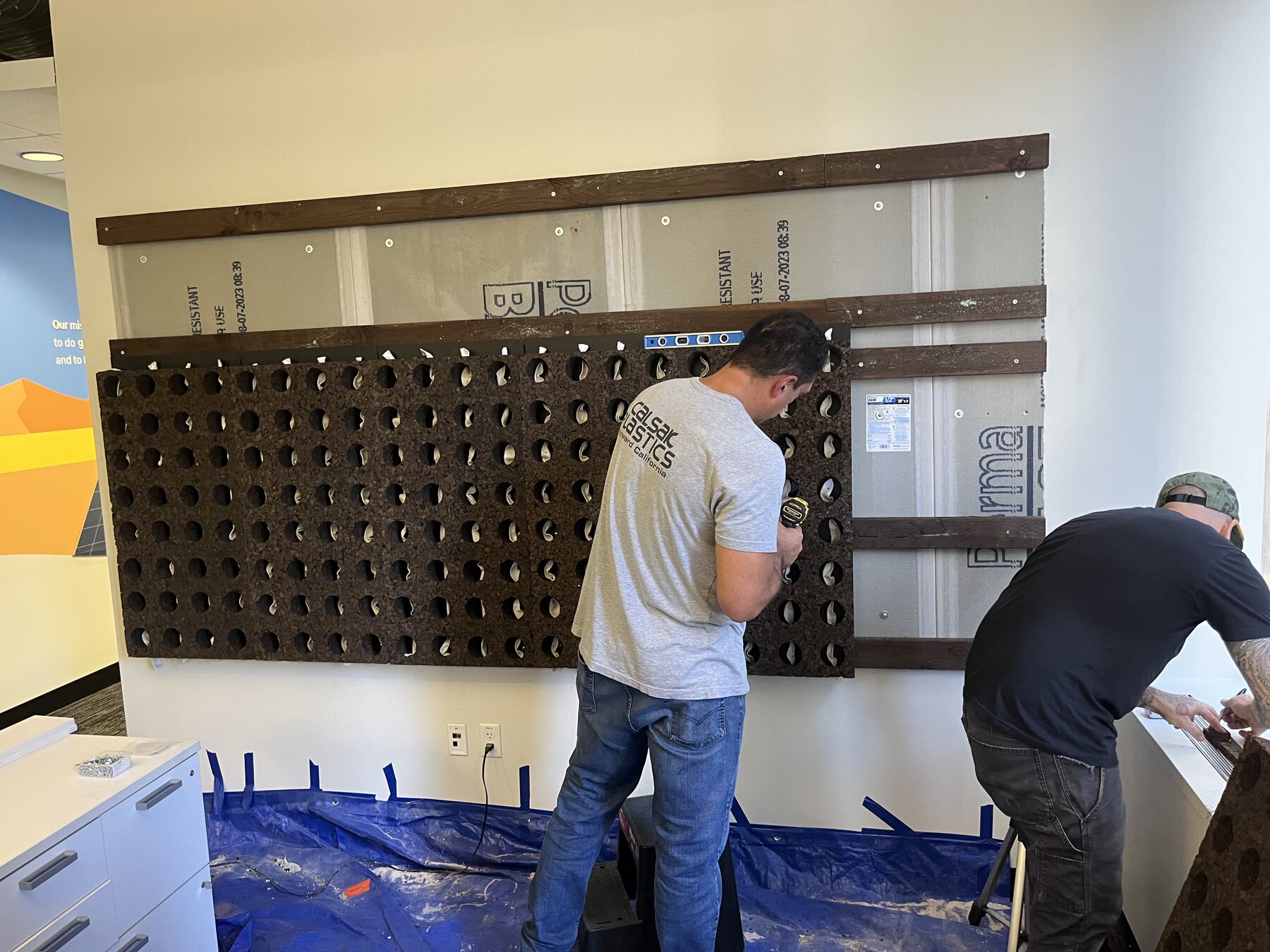 Installers mounting a dark dimensional grid over recognition panels