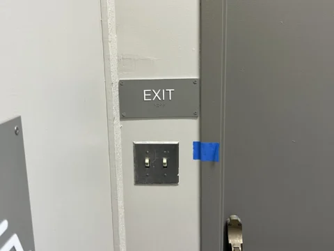Exit identification plaque installed beside a corridor door