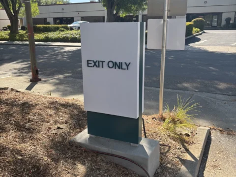 Exit Only directional monument sign beside a parking lot