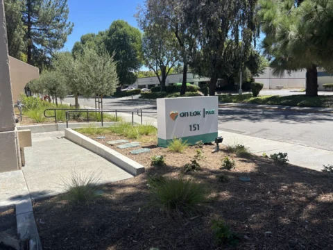 On Lok address 151 monument sign beside a landscaped walkway