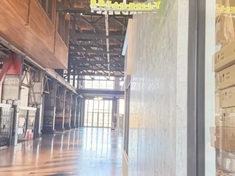 Illuminated Breadbelly blade sign installed along a commercial food hall corridor