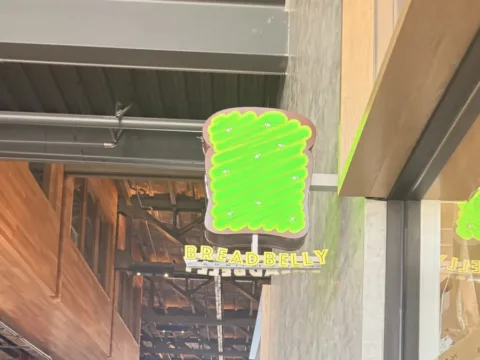 Illuminated Breadbelly blade sign installed along a commercial food hall corridor
