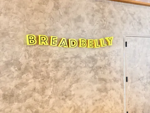 Yellow Breadbelly dimensional letters installed on a textured interior wall