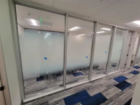 Gradient frosted privacy film installed across glass office walls in a commercial corridor