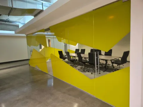 Yellow custom privacy film installed on a glass conference room enclosure