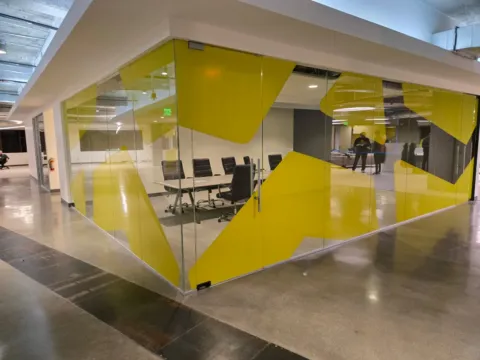 Yellow custom privacy film wrapping the glass walls of a commercial conference room